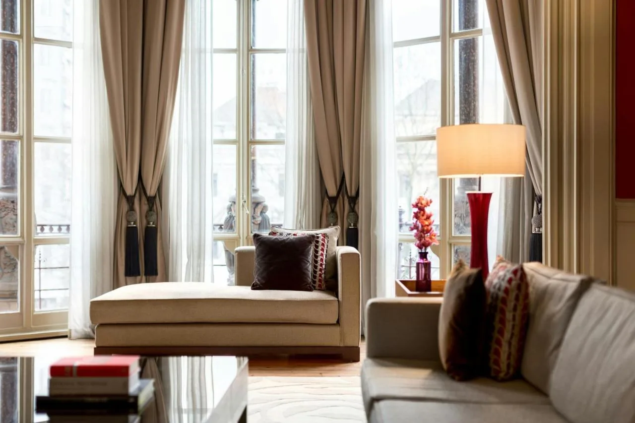 a living room with a couch and a lamp and windows at St Pancras London, Autograph Collection
