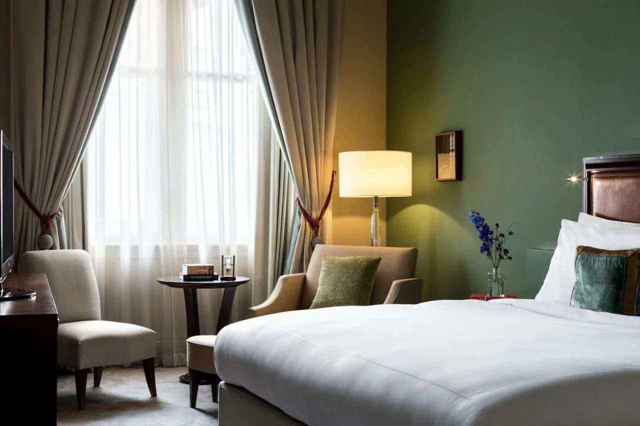 a hotel room with a bed and chairs and a window at St Pancras London, Autograph Collection
